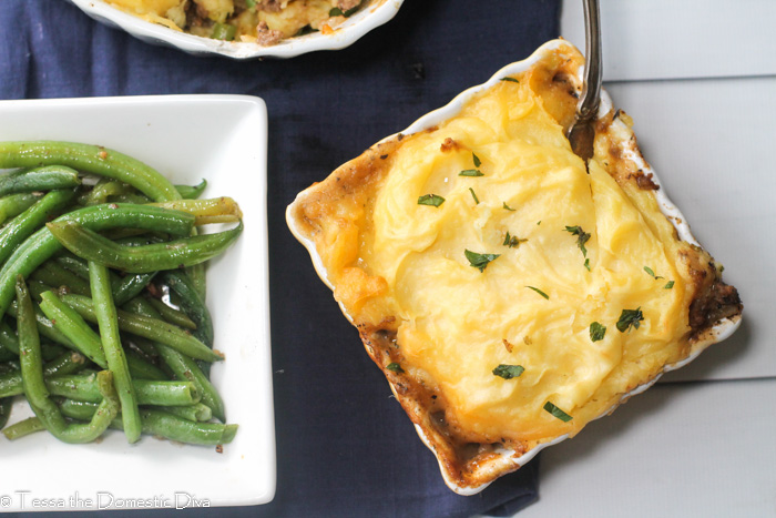 overhead view of a square ceramic baking dish with mased potato topped shepard's pie with a side of green beans