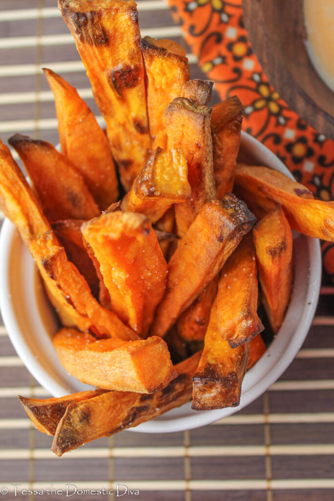 close up of crispy sweet potato fries from above on a deep orange fabric