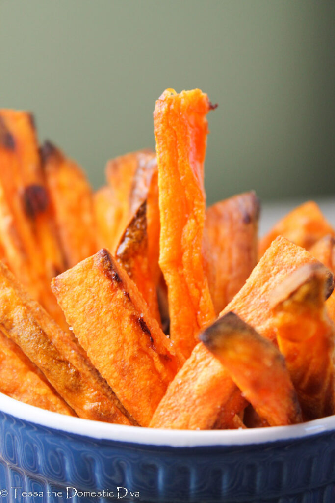 crispy sweet potato fries standing up in a dark blue ramekin