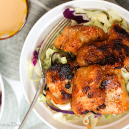 birds eye view of a white bowl filled with a creamy Cajun coleslaw with cripsy pan fried chicken breast bites