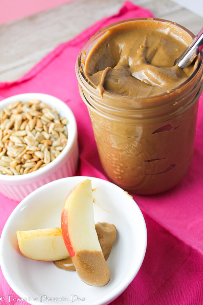 a glass mason jar with fresh made sunbutter and sliced apples 