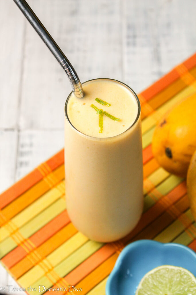 a tall clear glass filled with a creamy paleo orange smoothie with mango, lime, and kombucha