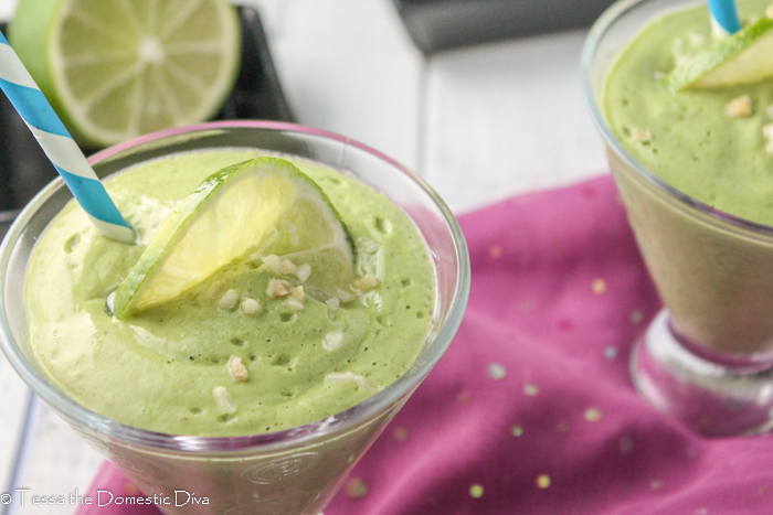 two clear glasses with tapered bottoms atop a purple sparkling cloth filled with a creamy lime avocado smoothie