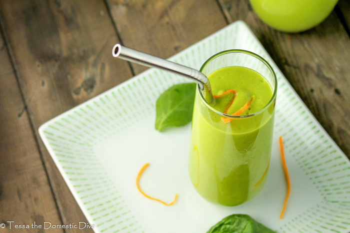 overhead view of a green smoothie with a zest of orange peel