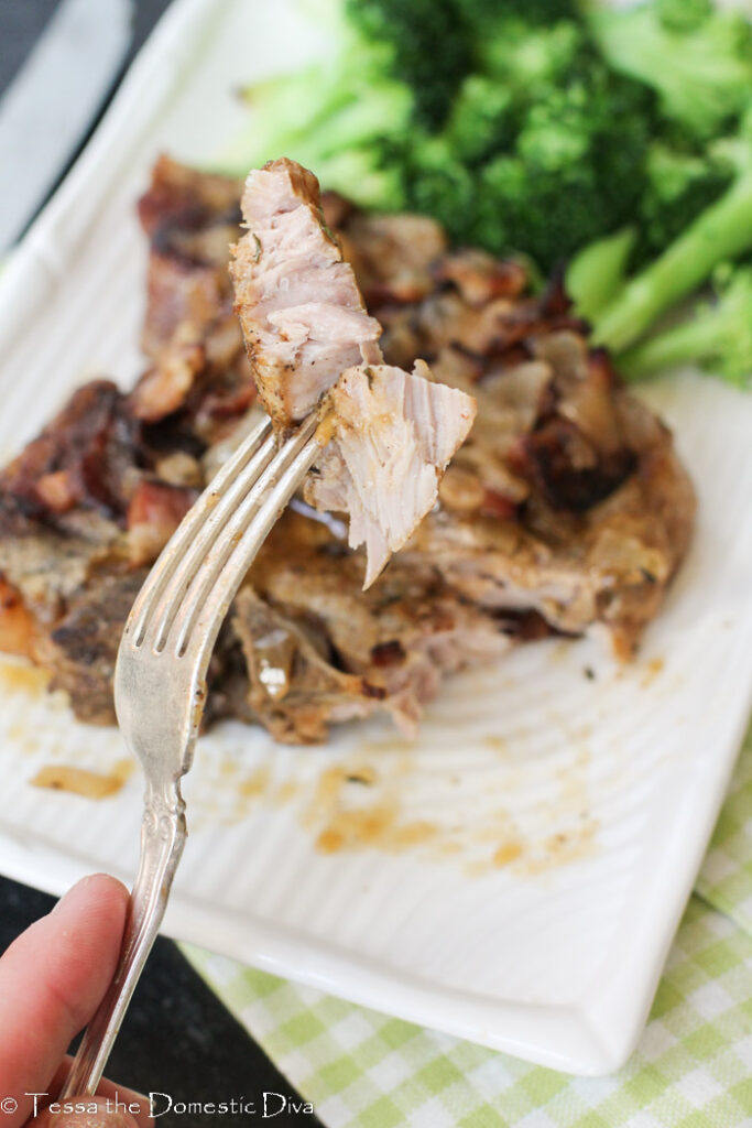 a fork full of tender pork chop up close with an Instant Pot in background.