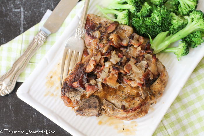 birds eye view of a pork chop topped with bacon and gravy on a white plate.