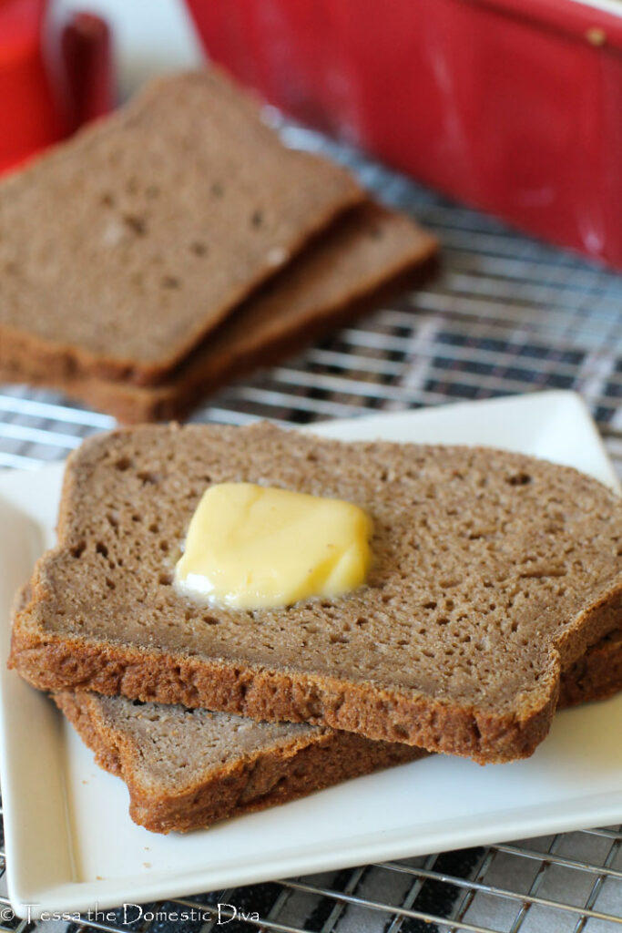 front view of two slices of wholesome gluten free bread with fresh butter on a white plate.