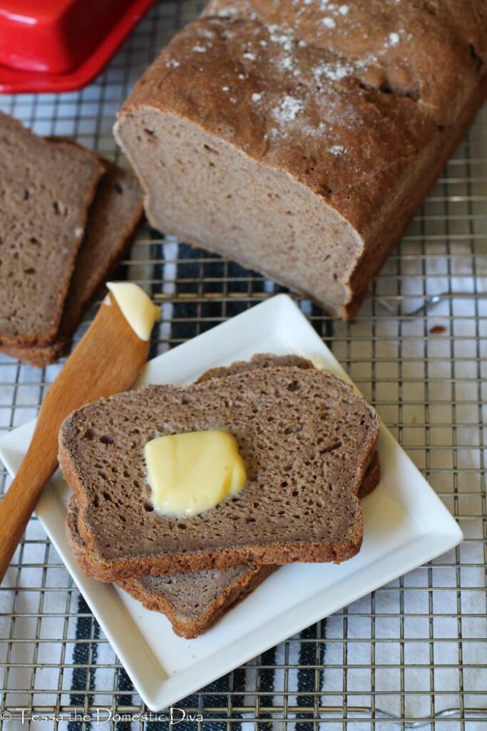 two slices of gluten free teff bread on a write plate with fresh butter.