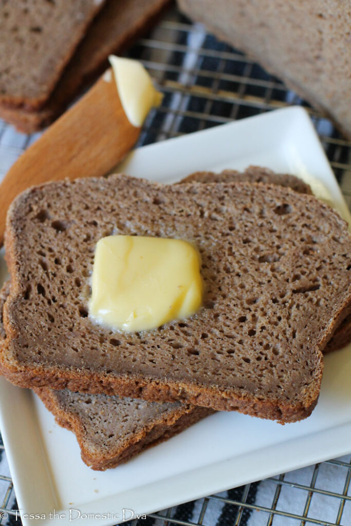 two slices of wholegrain gluten free bread on a white plate.