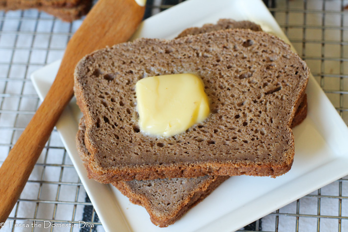 two slices of brown bread on a white plate with a pat of butter.