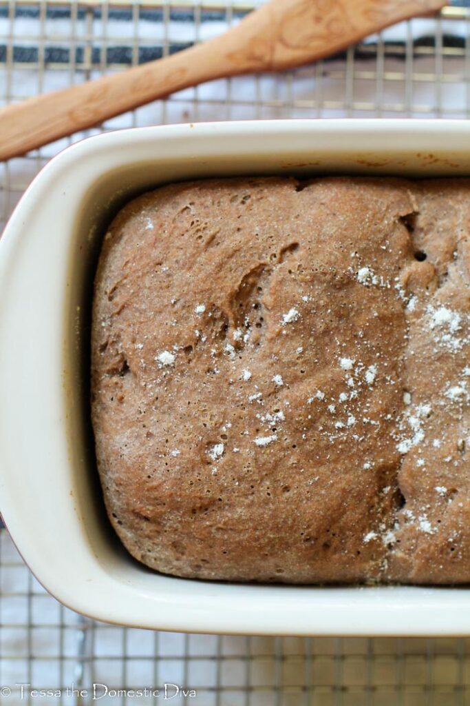 overhead view of a loaf of gluten free wholegrain bread in a ceramic pan.